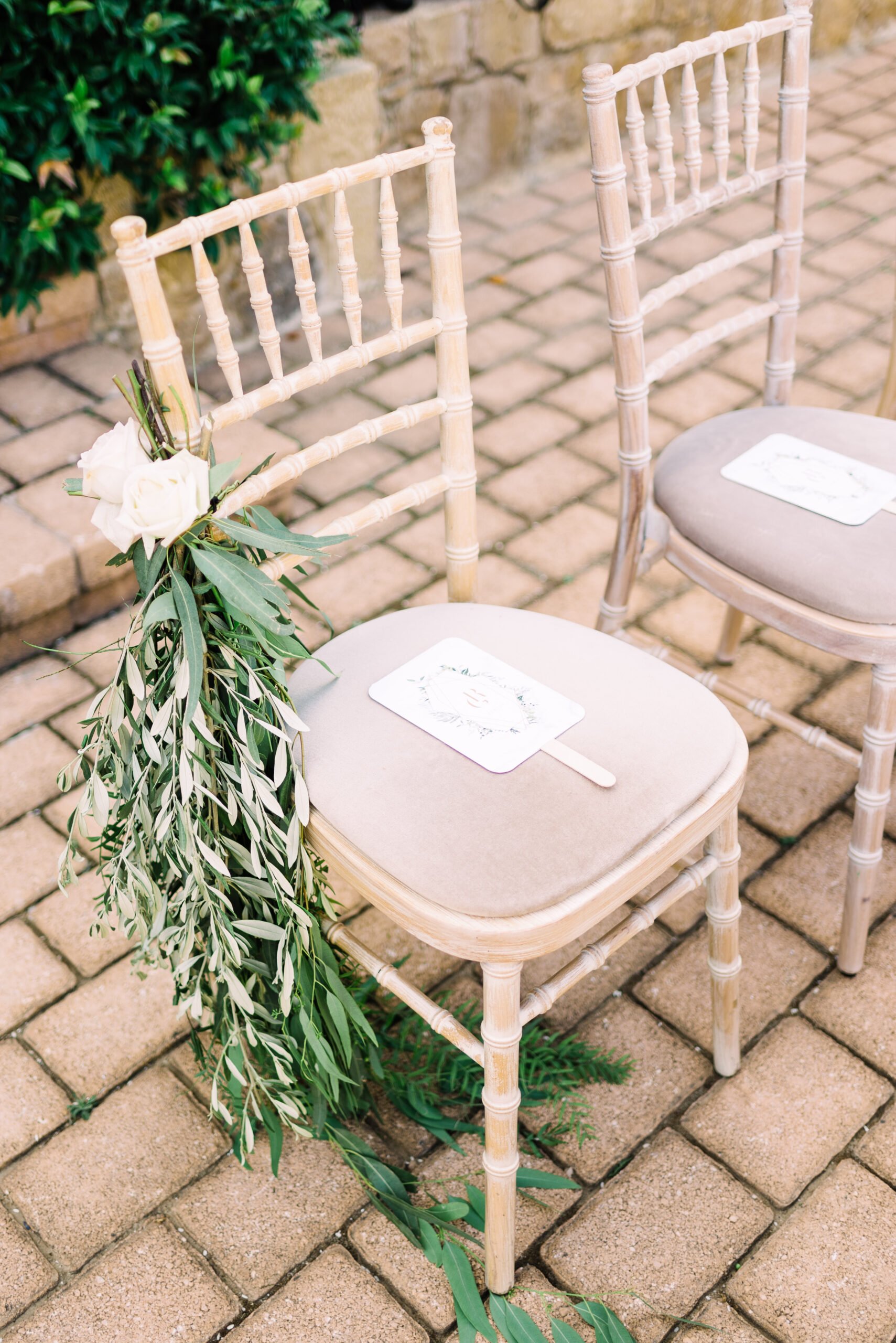 Καρέκλες tiffany στολισμένες με ευκάλυπτους και λευκά τριαντάφυλλα σε γάμο στο κτήμα casa e campo
